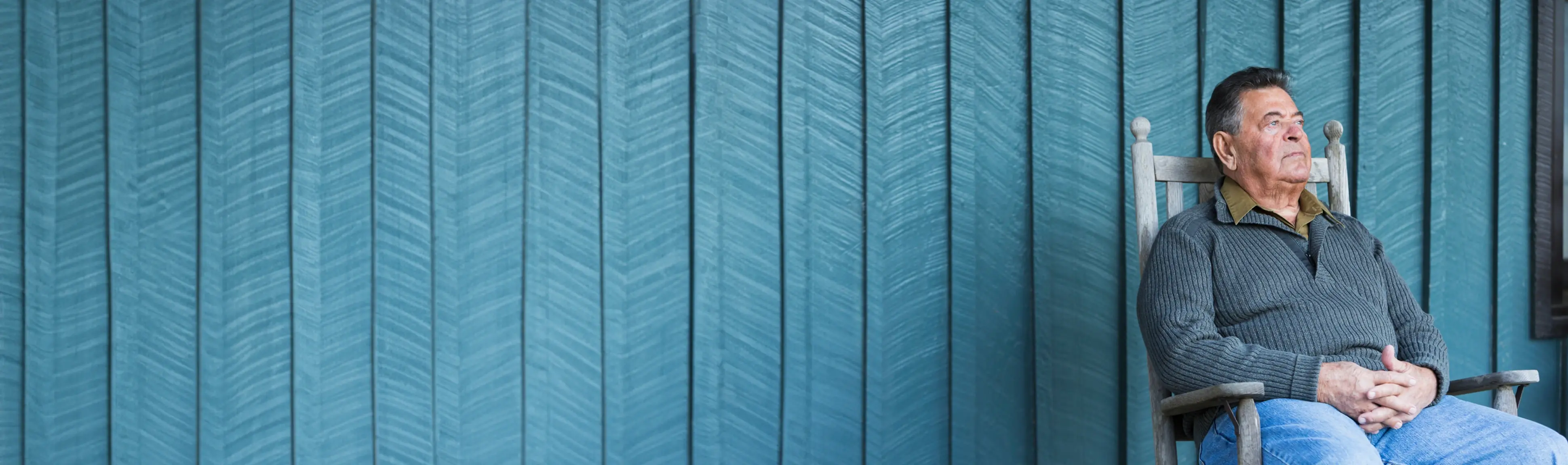 An elderly man sitting on a bench outside.