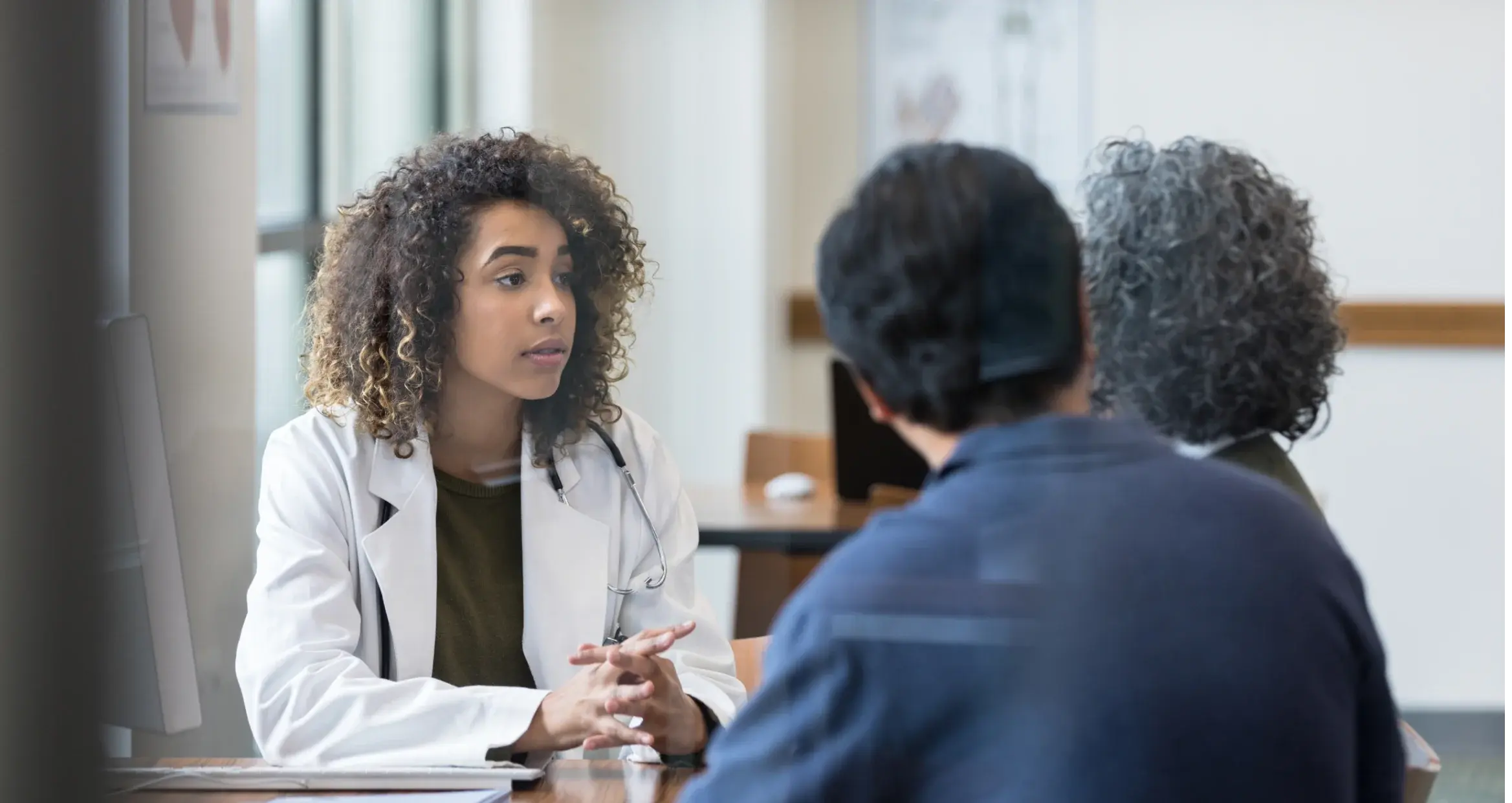  Il medico di mezza età ascolta con attenzione il suo paziente adulto che parla