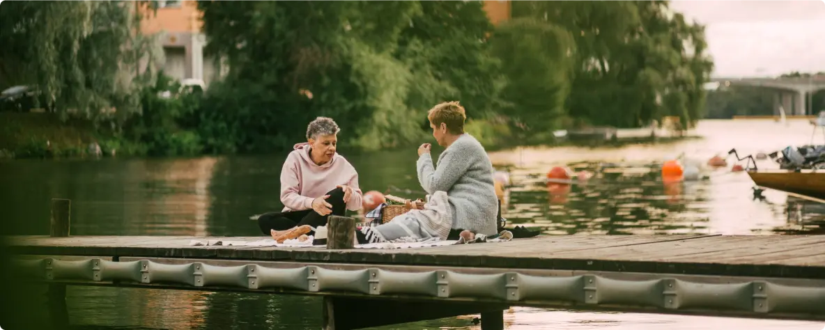 Zwei Frauen beim Picknick auf einem Bootssteg am See