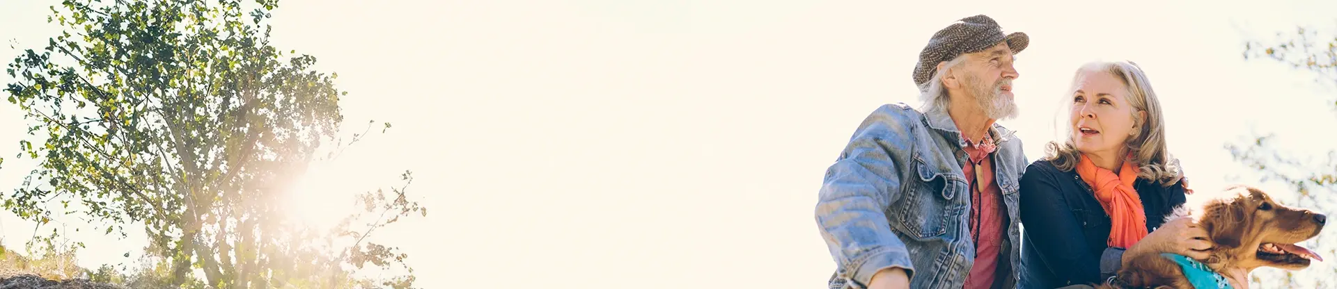 Ein älteres Paar sitzt zusammen mit ihrem Hund in der Natur 