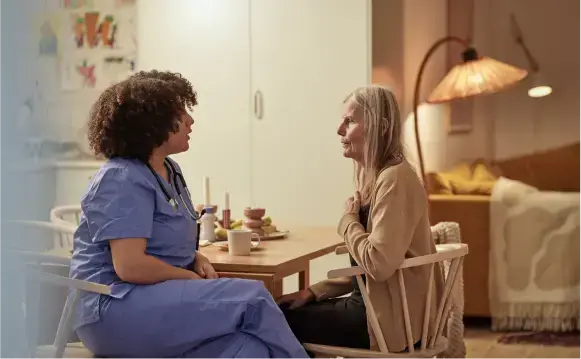 Une femme âgée assise en train de discuter avec une infirmière