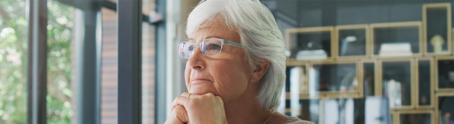 Femme âgée pensive les mains jointes, regardant devant elle