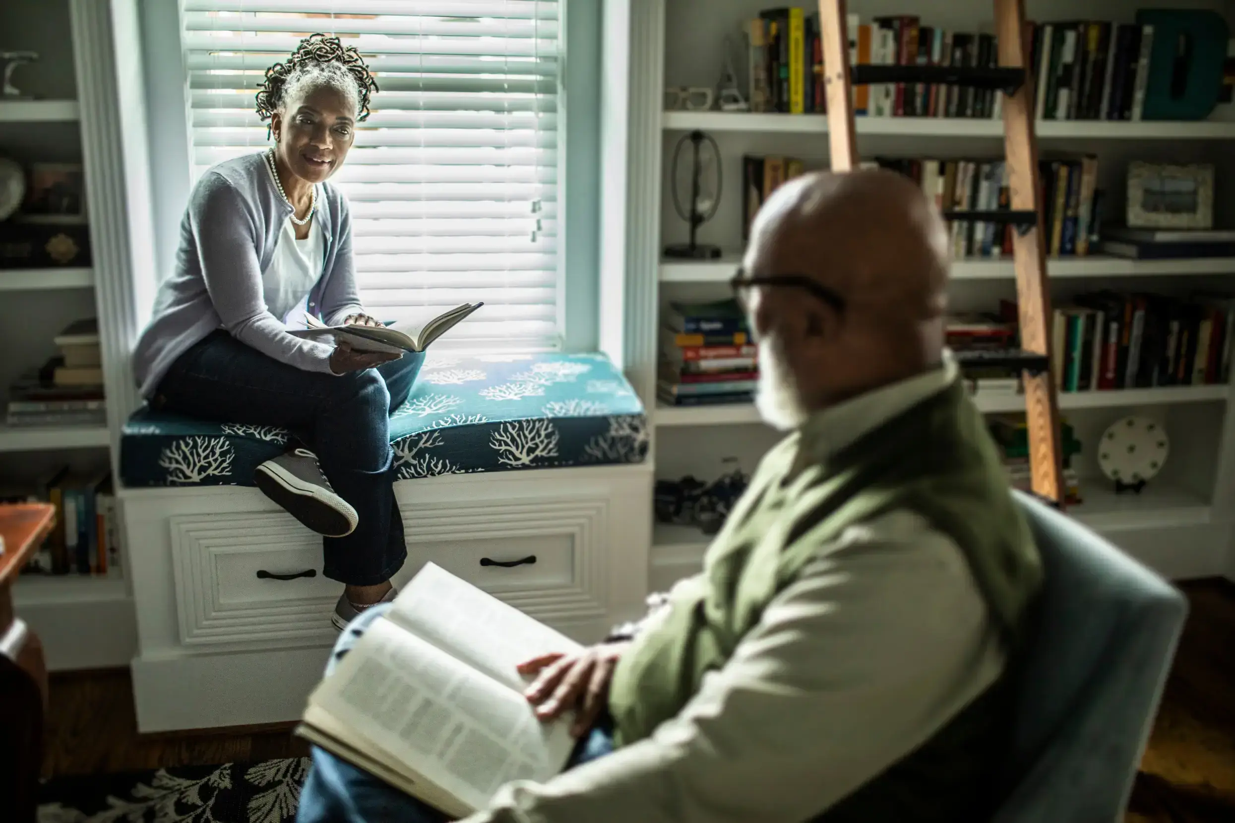 Un couple lisant dans la bibliothèque de la maison