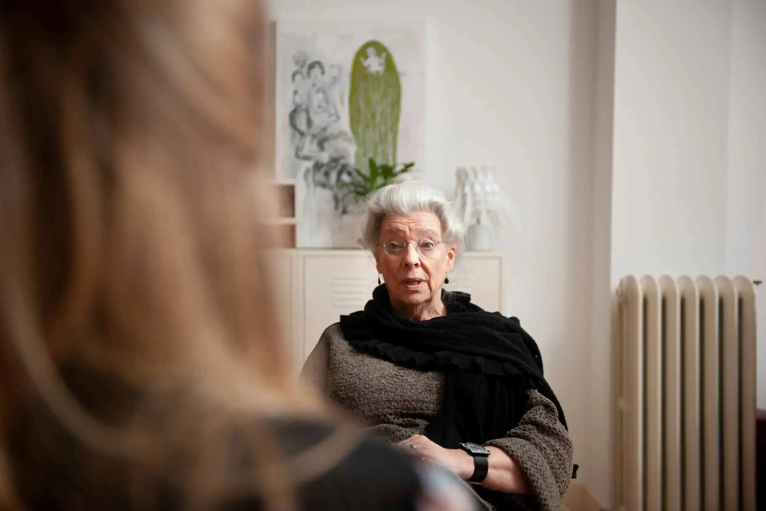 Vue par-dessus l'épaule d'une jeune femme assise en face d'un sympathique thérapeute/conseiller senior.